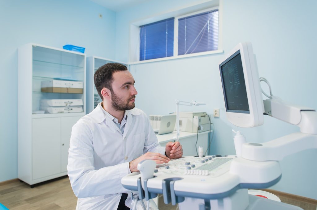Portrait of a thinking doctor near sceen of medical equipment.